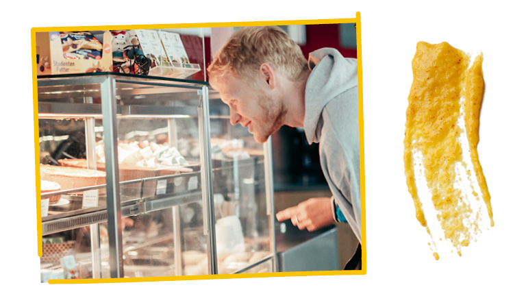 Foto zeigt einen Studenten, der in die Cafeteria-Vitrine schaut; daneben ist ein großer Senf-Klecks als Grafik zu sehen.